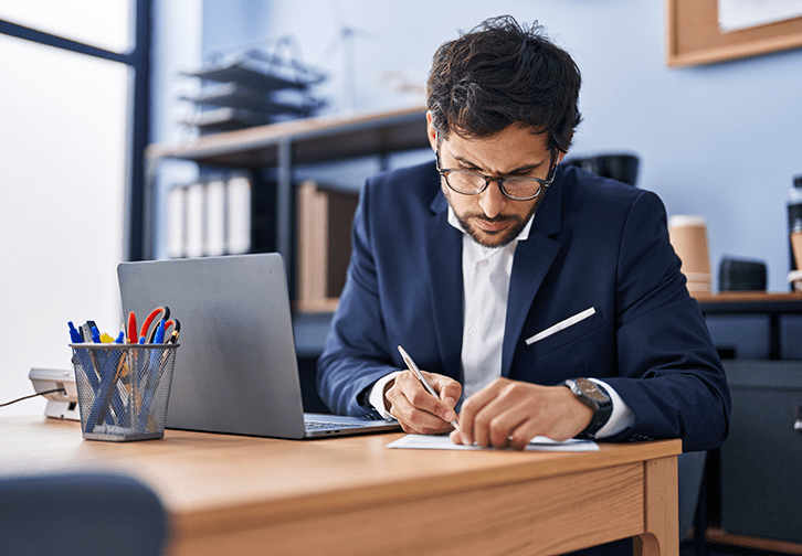 man looking intently at paper he is writing on