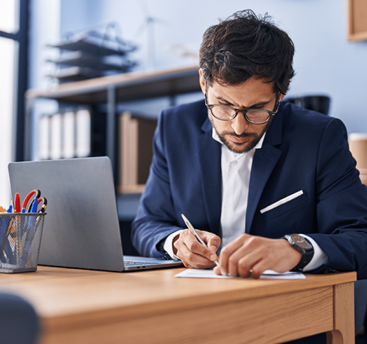 man looking intently at paper he is writing on