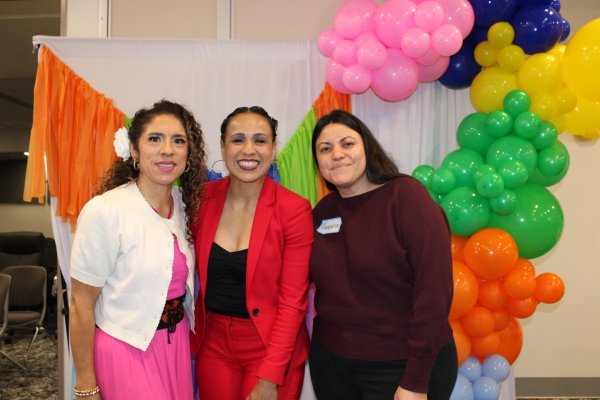 A group of three people smiling in front of balloons
